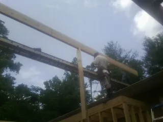 Carpenter setting a ridge beam over a new addition frame — Ice Dam Removal by Roofing Brothers in Greeley