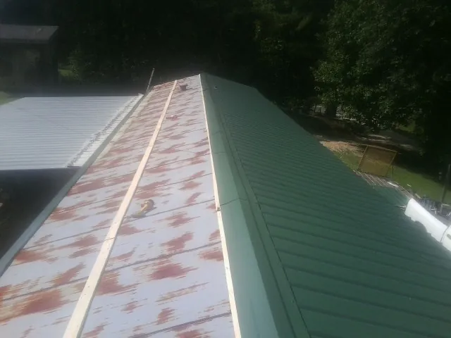 Old rusted panels beside newly installed green metal roofing — Wind Damage Roof Repair by Roofing Brothers in Greeley