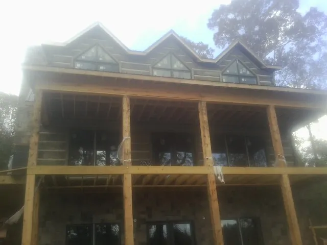 Dormers and porch framing on a large log home under construction — Roof Coating work by our crew in Greeley