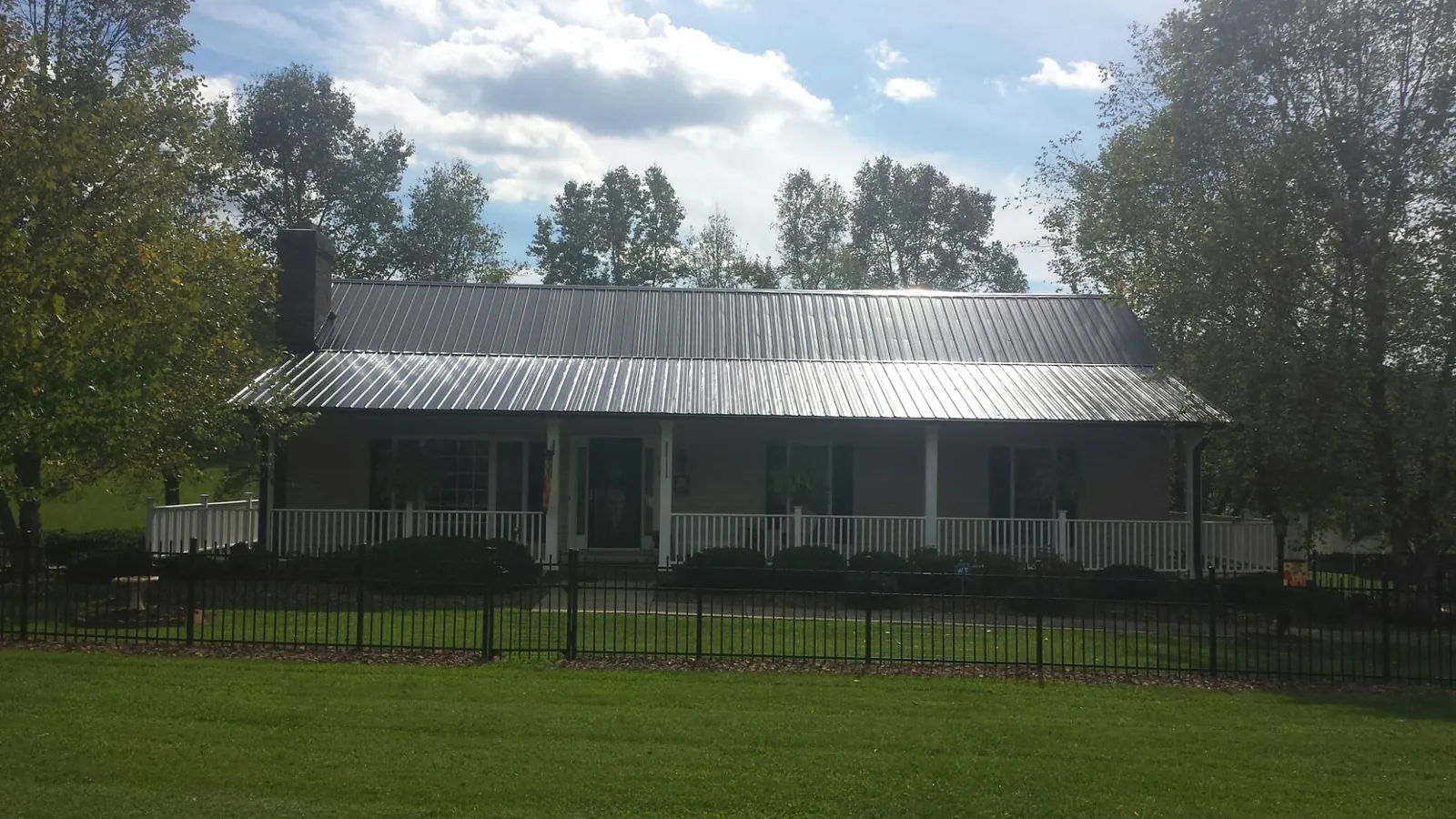 Gray metal roof on a brick ranch with a full width front porch — Gutter Guard Installation work by our crew in Greeley