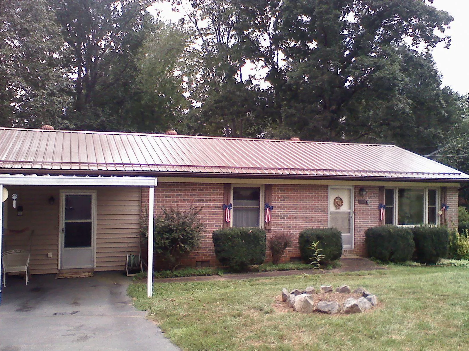 Bronze metal roof and carport on a brick ranch home — Roof Repair work by our crew in Greeley