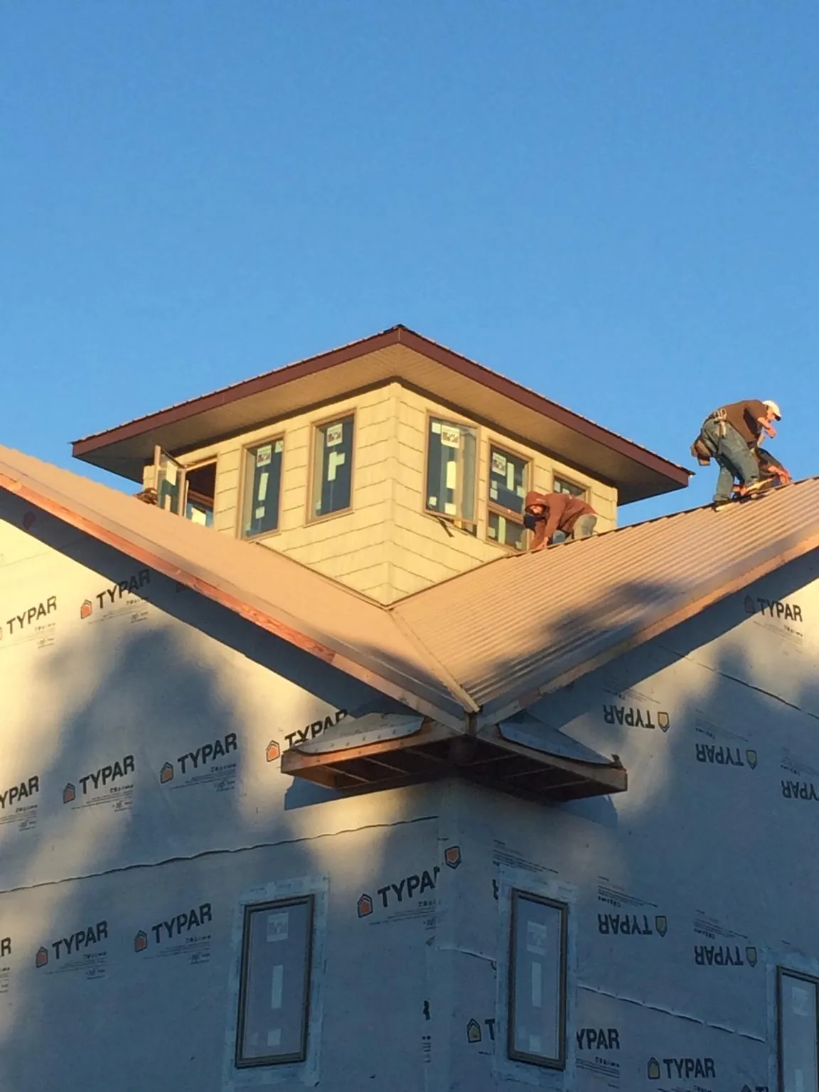 Roofers working around a rooftop cupola on a new metal roof at sunset — Roof Waterproofing in Greeley by Roofing Brothers